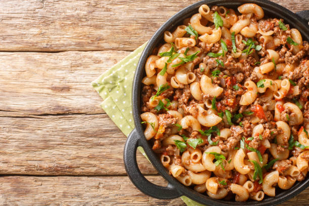 Hamburger Macaroni with with vegetables and cheese closeup in the pan. Horizontal top view