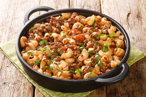 American Hamburger Goulash with Elbow Macaroni closeup in the pan on the wooden table. Horizontal