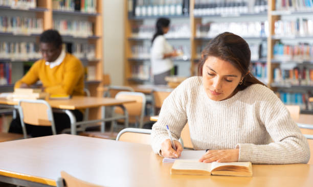istock Young latin american woman studying in university library 1428647189