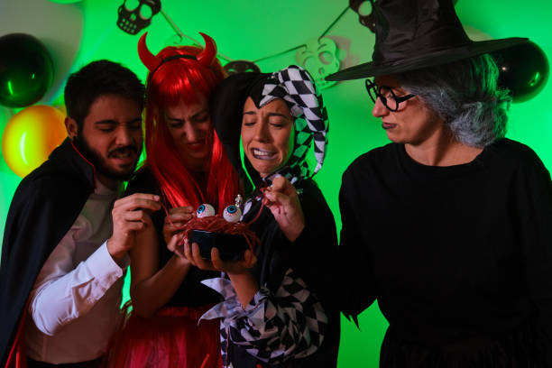 istock Four people look disgusted at a candy worms at a Halloween party. 1428651121