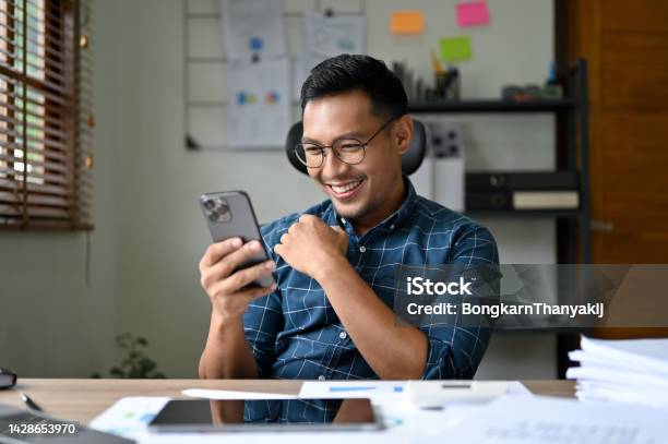 Handsome And Happy Asian Businessman Enjoys Chatting With His Girlfriend During Work Stock Photo - Download Image Now