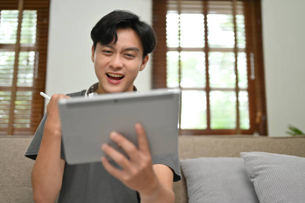 istock Excited and overjoyed Asian man looking at his tablet screen, screaming with overjoy 1428654068
