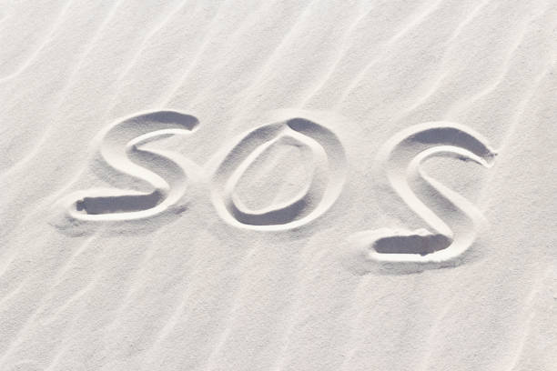 istock SOS written with finger on white sand, concept of missing and signal request for help, word on sand 1428655448
