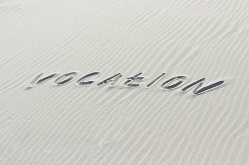 vocation written with finger on white sand, life path and choice concept, word on sand