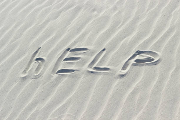 istock help written with finger on white sand, concept of missing and signal request for help, word on sand 1428655590