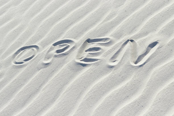 istock open written with finger on white sand, word on sand 1428655651