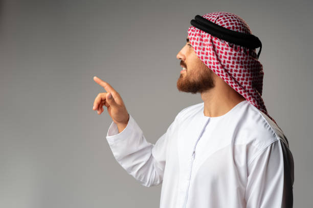 istock Young Arab man pointing hand to copy space on gray background 1428658803