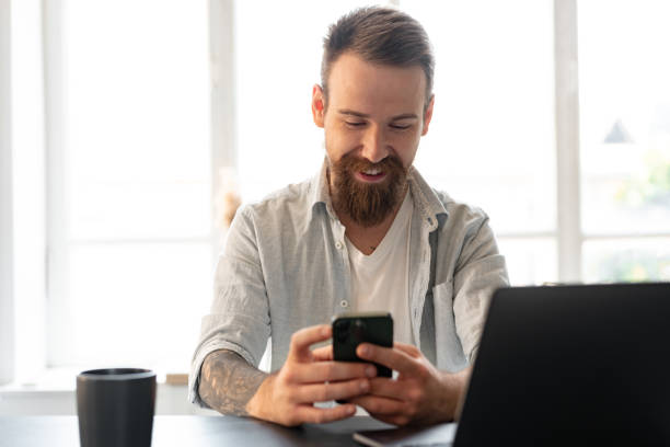 istock Handsome young bearded man spending time at home with phone in hands. 1428658827