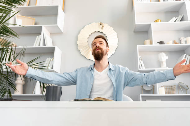 istock Young successful man sitting at the table raising his hands 1428658884