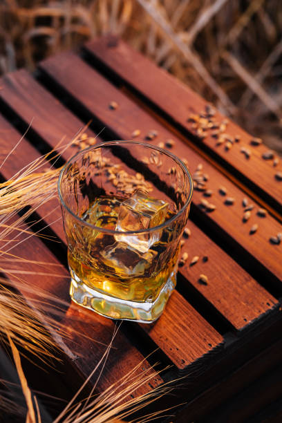 a glass of whiskey in a wheat field stock photo