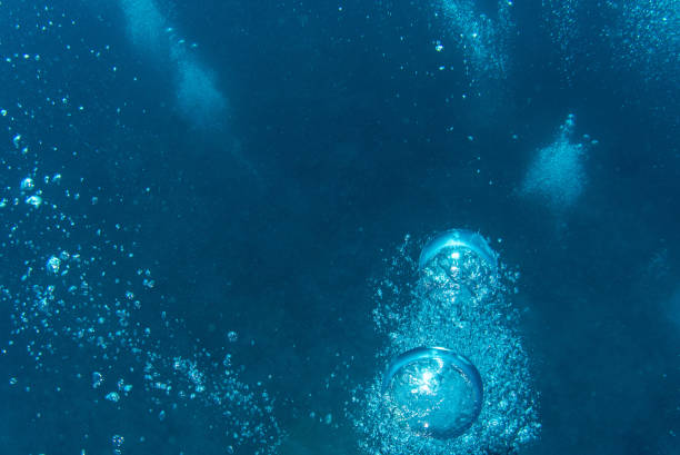 A scuba diver's exhaled air travels to the surface of the sea.  Air Bubble Blue sea Underwater sunlight background   Scuba diver point of view