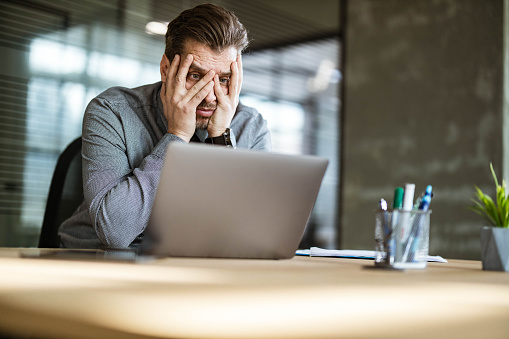 Displeased businessman reading a problematic e-mail on a computer in the office. Copy space.