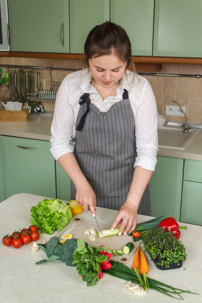 istock Woman cutting fresh vegetables for salad in kitchen 1428666340