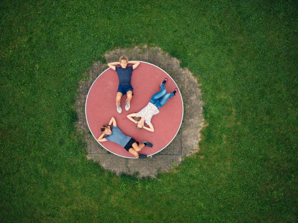 Three kids enjoying resting on playground wheel carousel