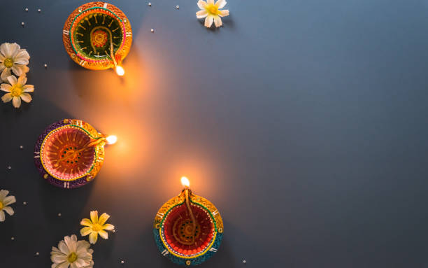 Happy Diwali - Clay Diya lamps lit during Diwali, Hindu festival of lights celebration. Colorful traditional oil lamp diya on blue background Happy Diwali - Clay Diya lamps lit during Diwali, Hindu festival of lights celebration. Colorful traditional oil lamp diya on blue background diwali photos stock pictures, royalty-free photos & images