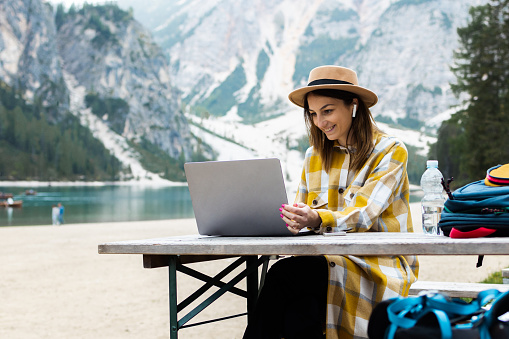 Portrait of a young woman enjoying her vacation on the mountain and studying online