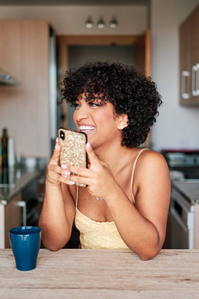 istock Transgender woman using a mobile phone and smiling while sitting at kitchen table. 1428669352