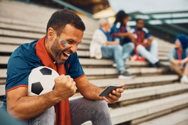 istock Passionate soccer fan cheering while watching a match on mobile phone. 1428669483