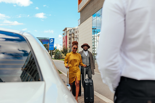 A wealthy African American couple are being picked up at the airport by their limo driver. They just landed with their private jet to go for a vacation.