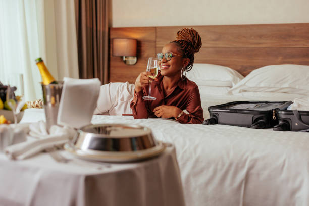 femme avec du champagne allongée sur le lit de l’hôtel. - relaxation success luxury women photos et images de collection