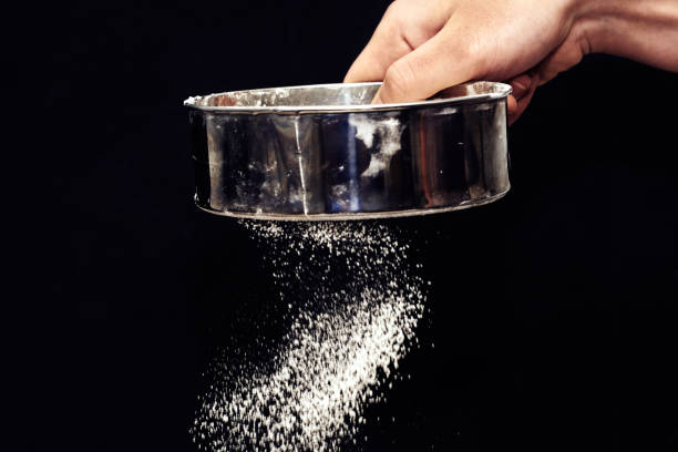 istock a man sifts flour through a sieve on a black background 1428675502
