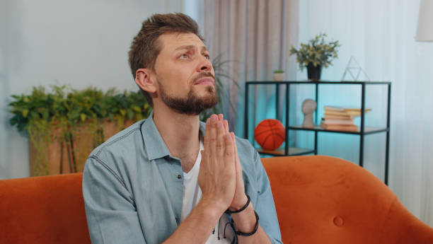 istock Young man praying sincerely with folded arms asking God for help, begging apology, making a wish 1428676522