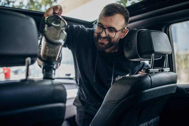 istock Young Man Cleaning car with cordless stick vacuum cleaner 1428683563