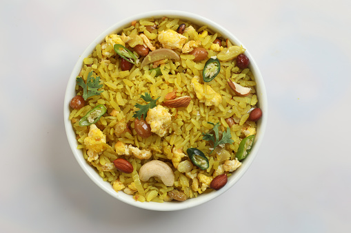 indian breakfast dish poha.Indian breakfast Poha topped with peanuts, pomegranate seeds, chopped green chilly, onion, lime, coriander leaves and curry leaves.