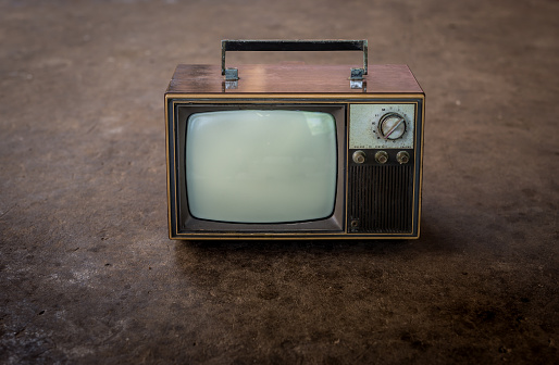 Old black vintage TV set against wallpaper and carpet 1980-1990 background.