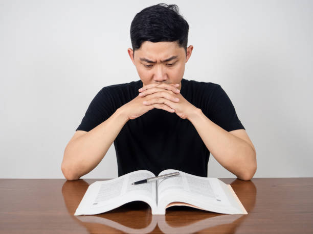 istock Asian man seriously about reading text book on the table 1428702566