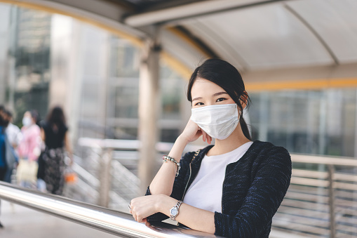 Portrait of beautiful young adult asian woman wear face mask for new normal lifestyle. Casual business look with accessories and watch.