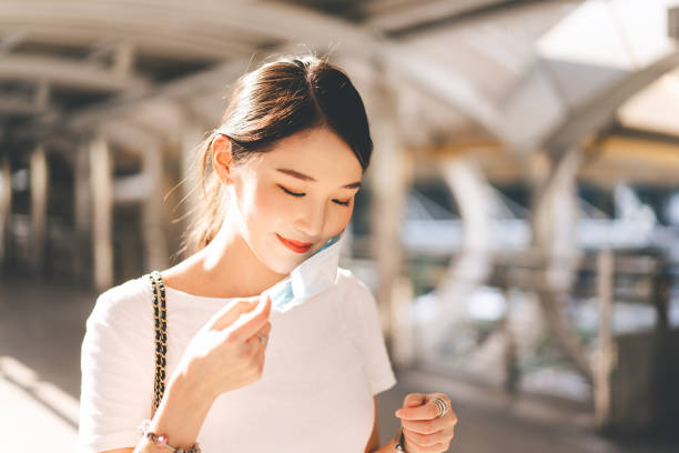 jovem adulto negócio sudeste asiático mulher bonita vestindo ou remover máscara facial - southeast asian ethnicity fotos - fotografias e filmes do acervo