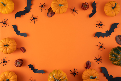 Halloween decorations, pumpkins, bats, ghosts on orange background with copy space