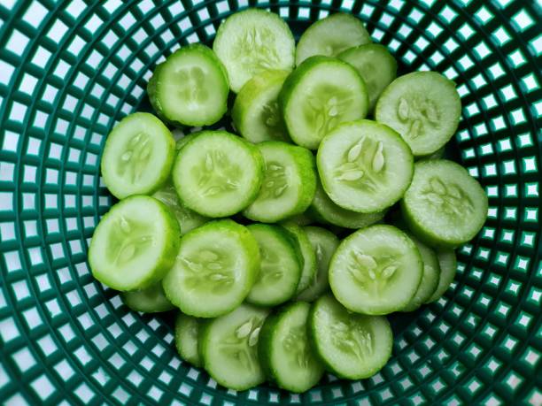 Sliced Cucumbers in dark green basket - food preparation. stock photo