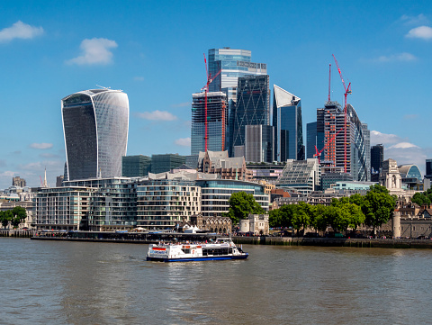 Some of the taller buildings in the City of London with a tourboat advancing towards Tower Millennium Pier beside the Tower of London.