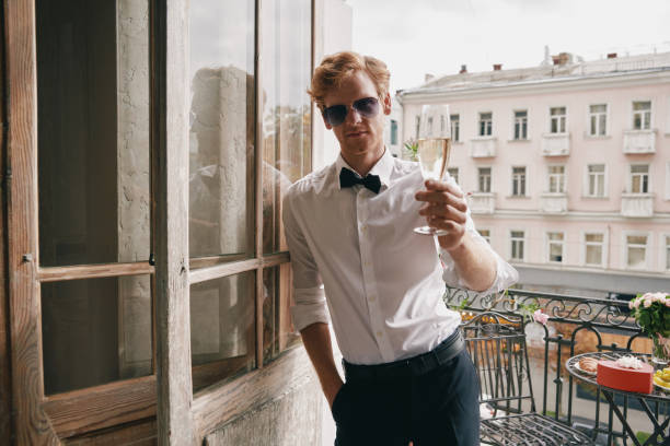 istock Handsome young man toasting with champagne while leaning at the balcony door 1428719493