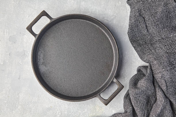 istock Black cast iron empty frying pan and gray kitchen towel on a gray concrete background 1428720401