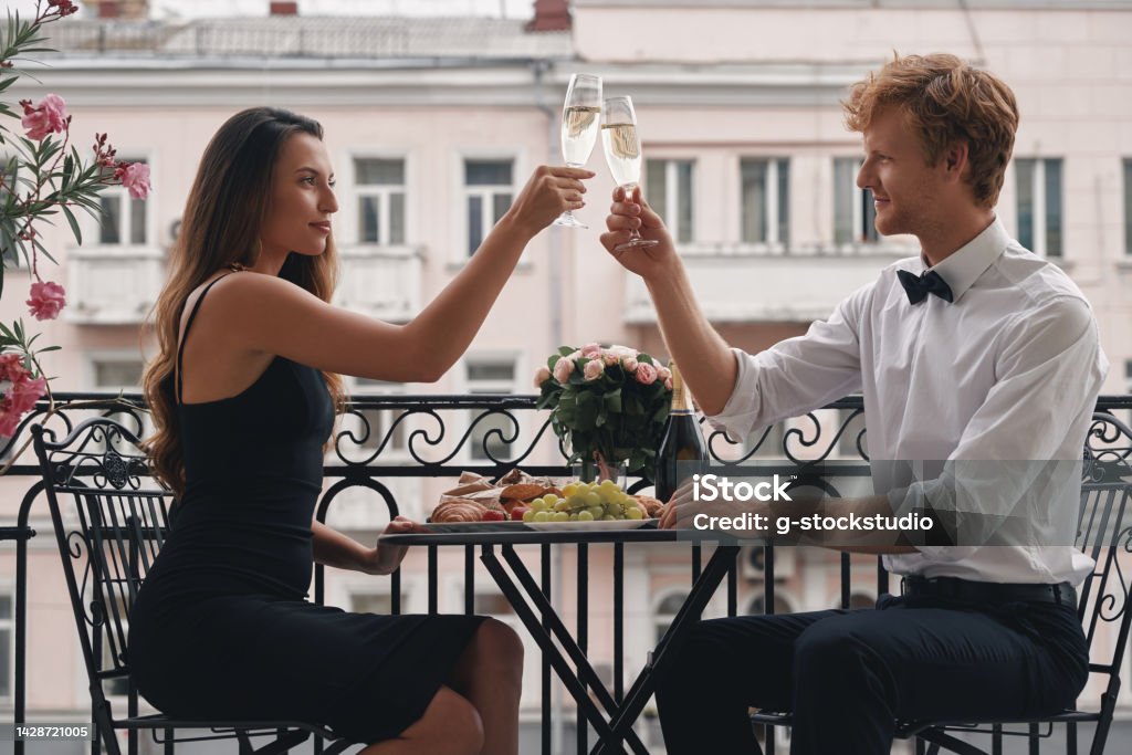 Young loving couple toasting with champagne while having a romantic dinner on the balcony Adults Only Stock Photo
