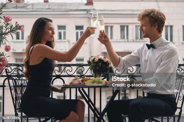 Young Loving Couple Toasting With Champagne While Having A Romantic Dinner On The Balcony Stock Photo - Download Image Now