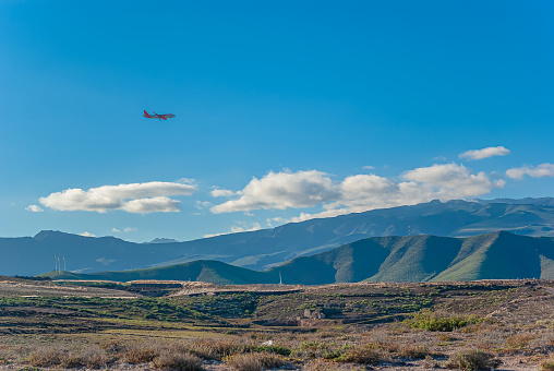 Picturesque mountain landscape. Airplane over mountains. Wind turbines on coast. Alternative energy.