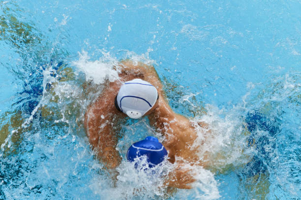 Two male water polo players wrestle and fight for the position.