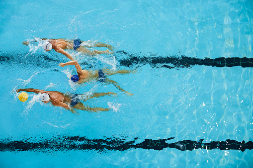Synchronized swimming team jumping into the pool on their side.