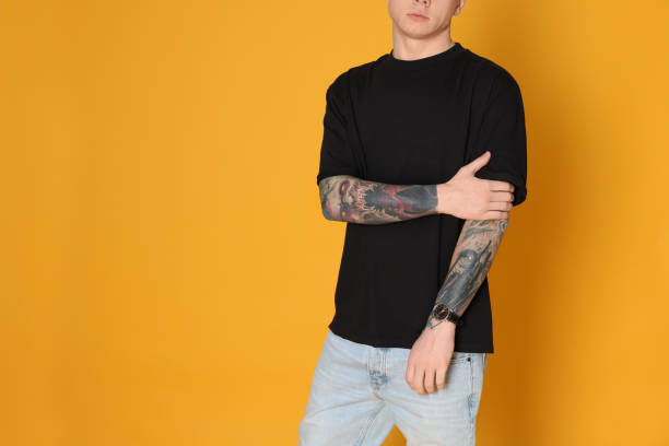 istock Man with stylish tattoos on yellow background, closeup. Space for text 1428724722