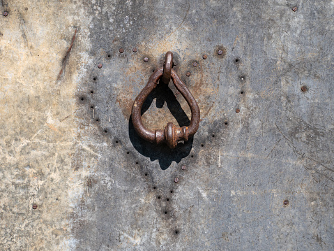 Old rusted door handle with rusting nails surrounded in a heart shape