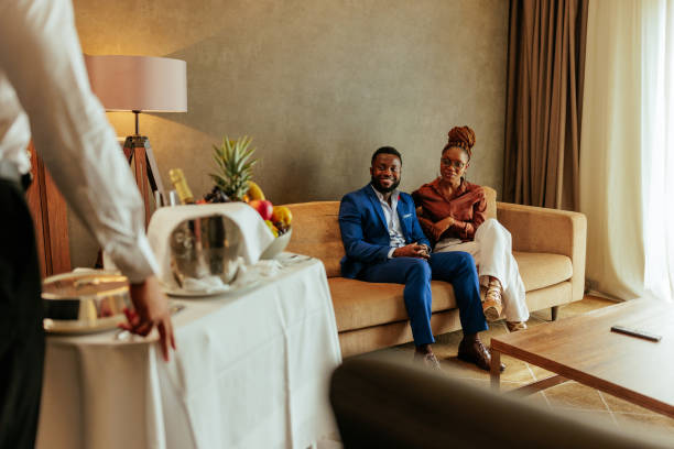 Wealthy couple catered with room service A wealthy African American couple is in their hotel room being catered with luxurious room service. They are very stylish and are relaxing on the sofa. room service stock pictures, royalty-free photos & images