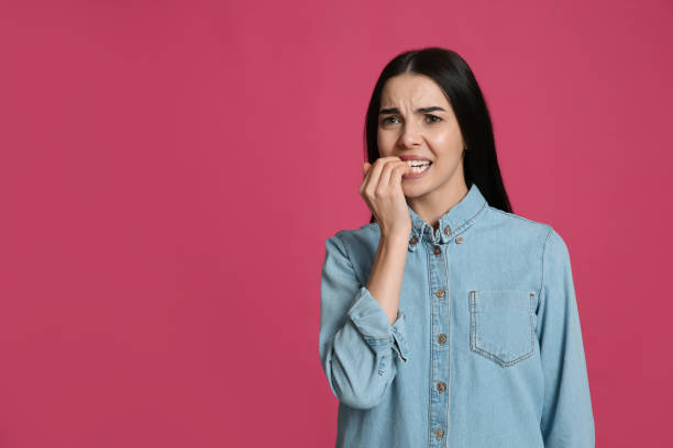 Young woman biting her nails on pink background. Space for text Young woman biting her nails on pink background. Space for text nail biting stock pictures, royalty-free photos & images