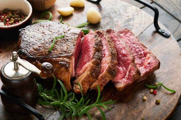 Steaks. Sliced grilled meat steak New York or Striploin with spices rosemary and pepper on black marble board on old wooden background. Top view. Mock up. Steaks. Sliced grilled meat steak New York or Striploin with spices rosemary and pepper on black marble board on old wooden background. Top view. Mock up. sirloin steak stock pictures, royalty-free photos & images