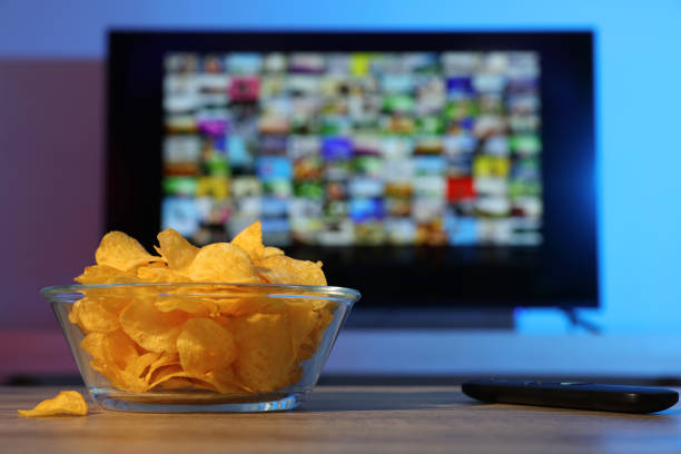istock Bowl of chips and TV remote control on table indoors 1428733005
