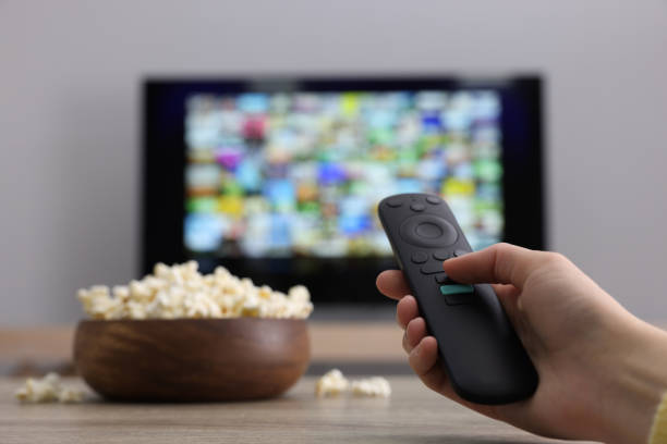 istock Woman switching channels on TV set with remote control at home, closeup. Space for text 1428733164