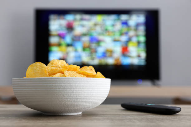 istock Bowl of chips and TV remote control on table indoors 1428733192